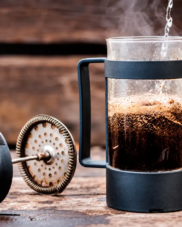 French press with ground coffee and the plunger removed