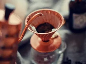 Hot water being poured into a copper-coloured Hario V60 dripper