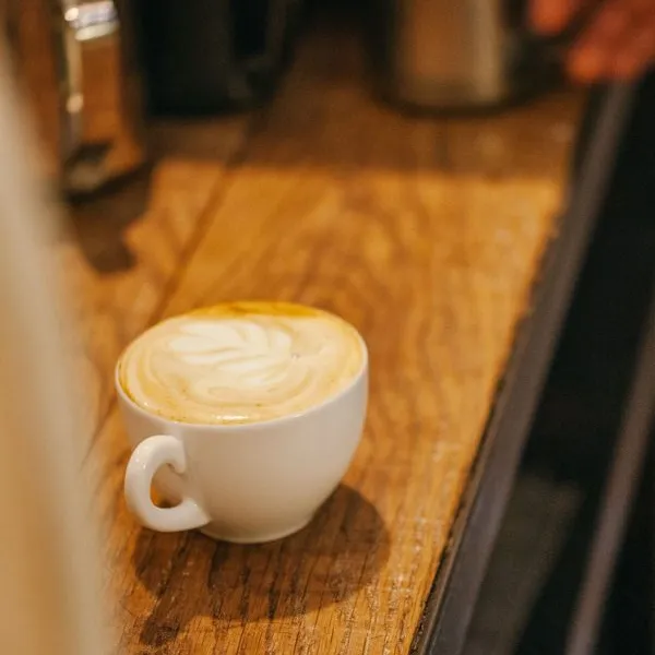 White cappuccino cup with latte art on a wooden coffee bar