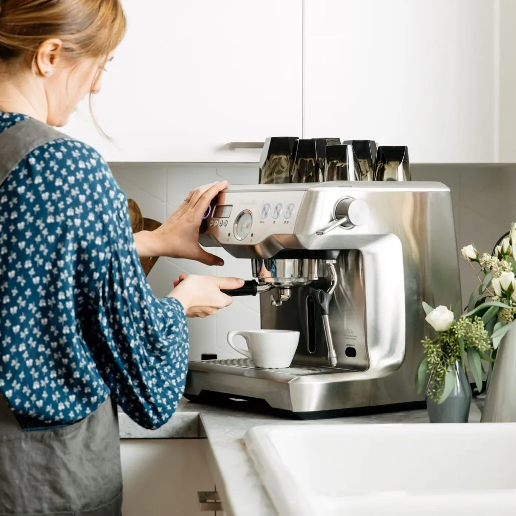 Person preparing coffee with an espresso machine at a café counter