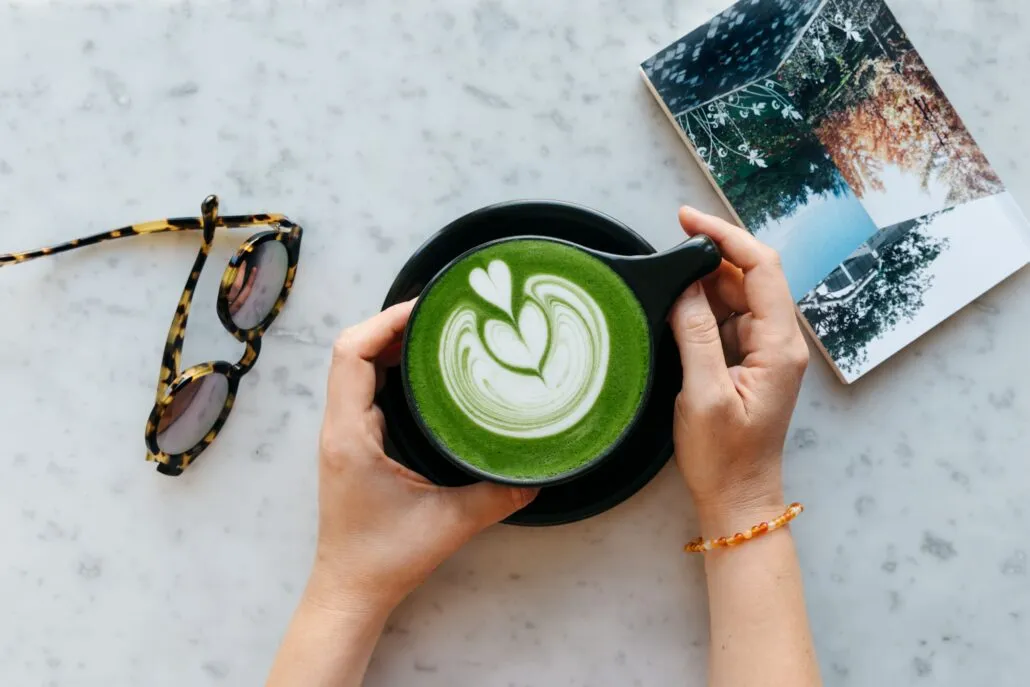 Overhead view of a person holding a black notNeutral Lino cup with a green drink and latte art