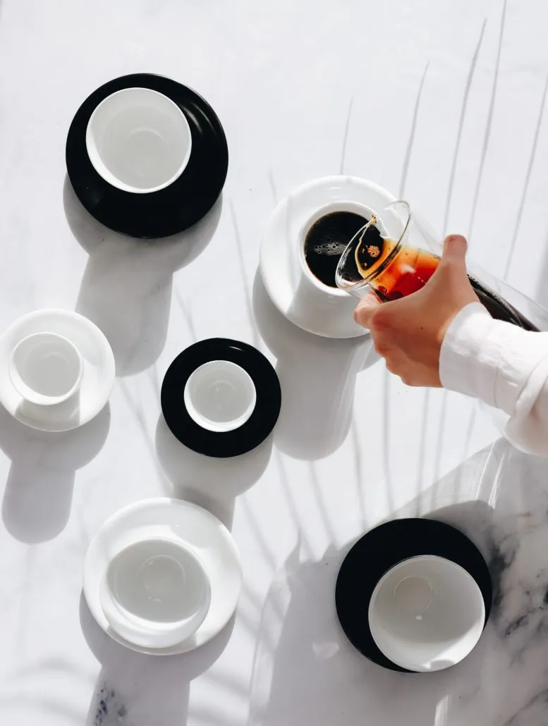 Black and white handle-free coffee cups arranged on a white table